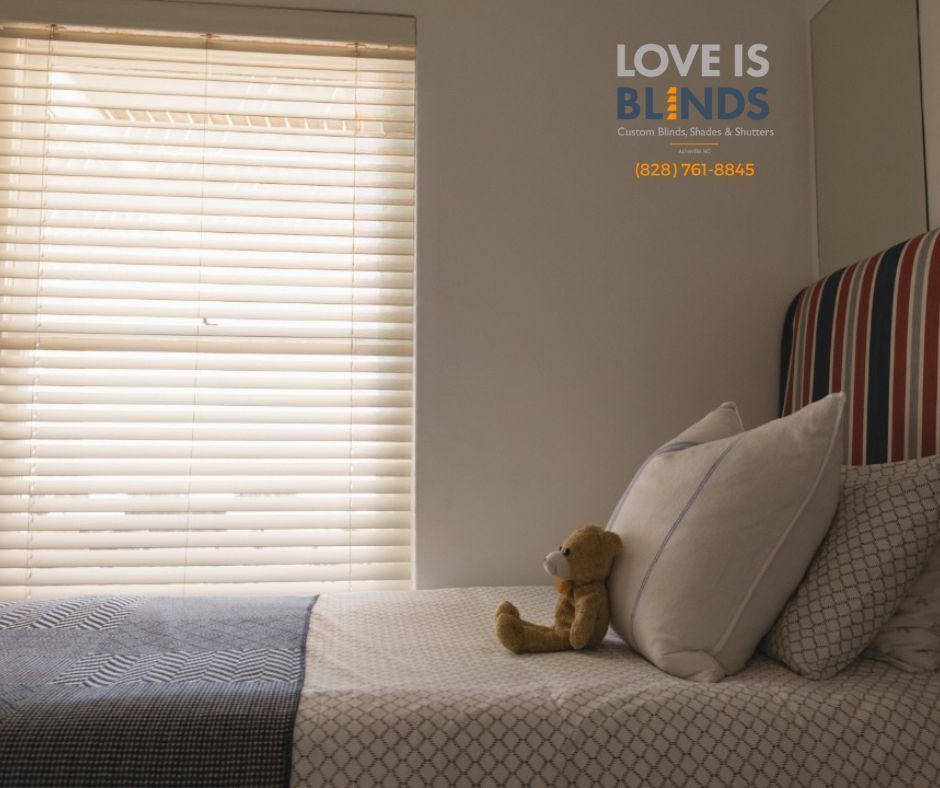 Cozy bedroom with bed, striped headboard, window blinds, teddy bear, and “LOVE IS BLINDS” wall text.