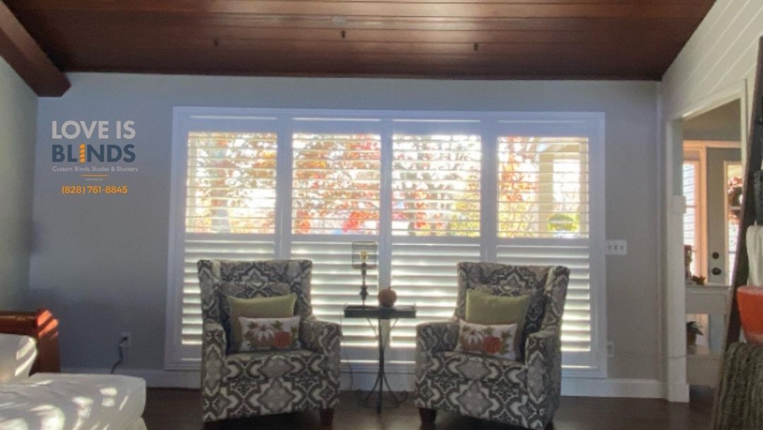 Two patterned armchairs face a window; a small table sits between them.