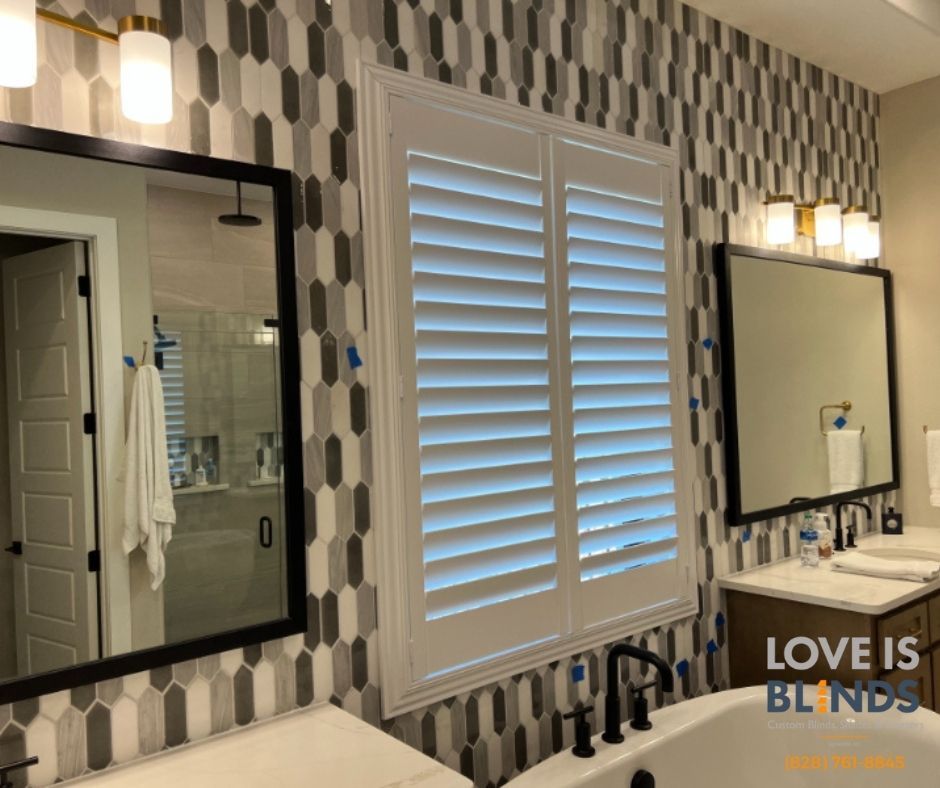 Modern bathroom with patterned wallpaper, double mirrors, vanity lights, and white plantation shutters