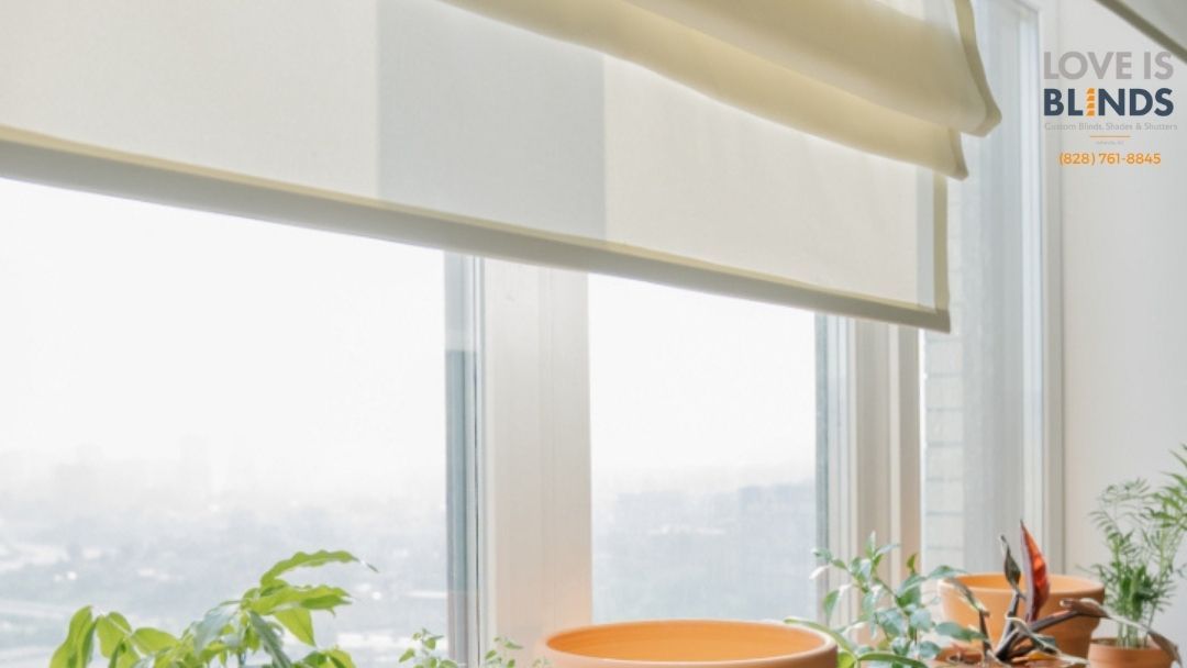Cream Roman blind above a bright window with potted plants on the sill