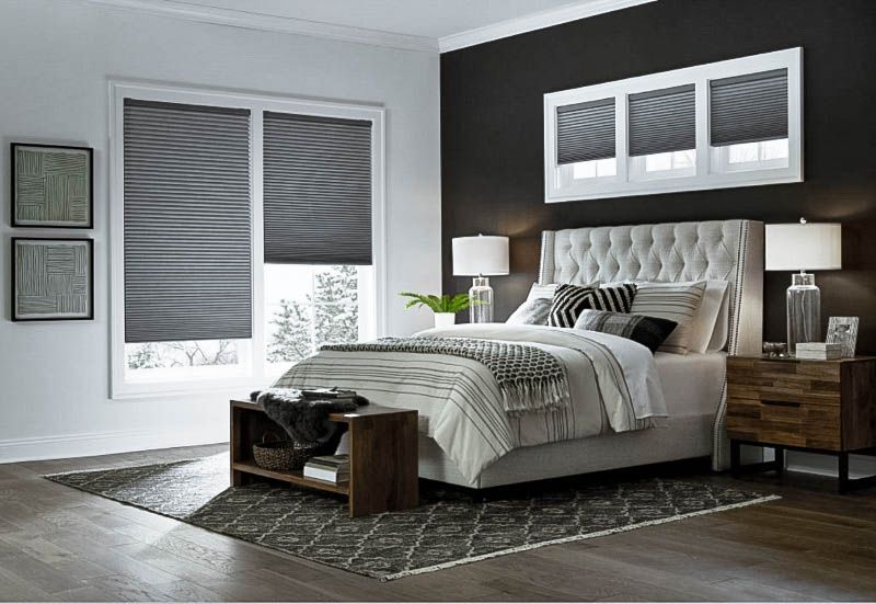 A bedroom with a bed , nightstand , and window shades. Love is Blinds of Western NC 866-756-6299.