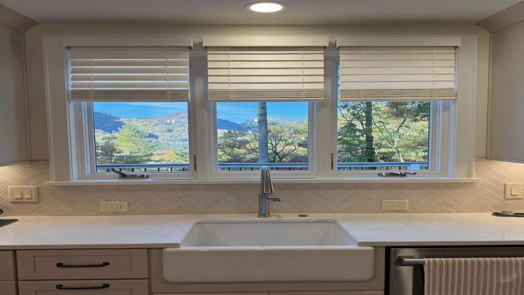 Modern kitchen sink beneath large windows with a mountain view outside