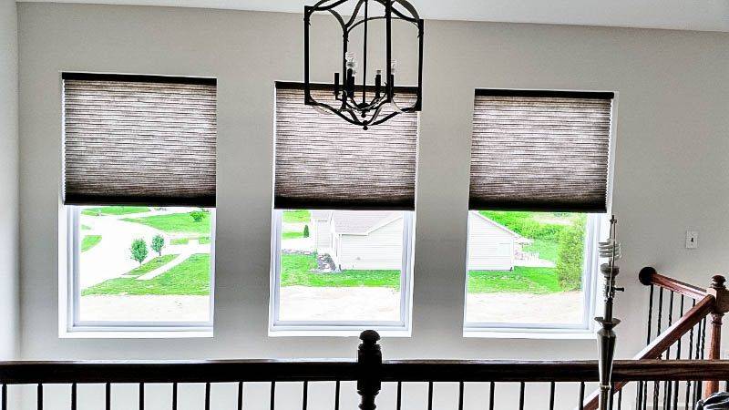 A staircase with three windows and a chandelier hanging from the ceiling. Love is Blinds of Western NC 866-756-6299.
