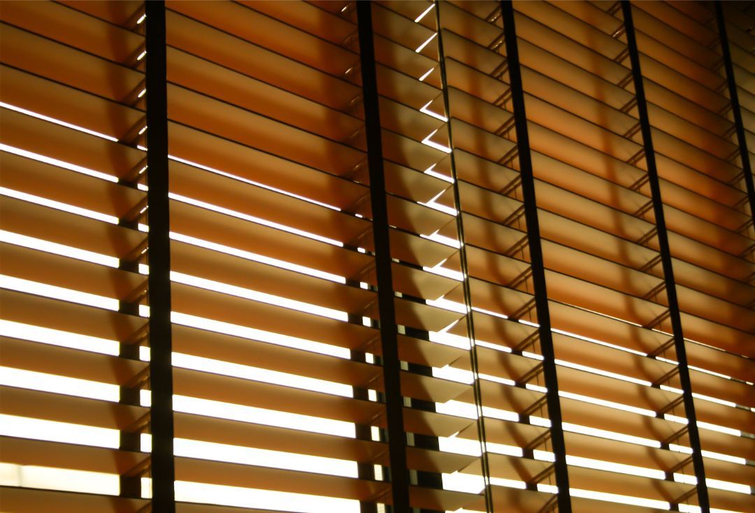 Wooden window blinds with warm sunlight streaming through the slats