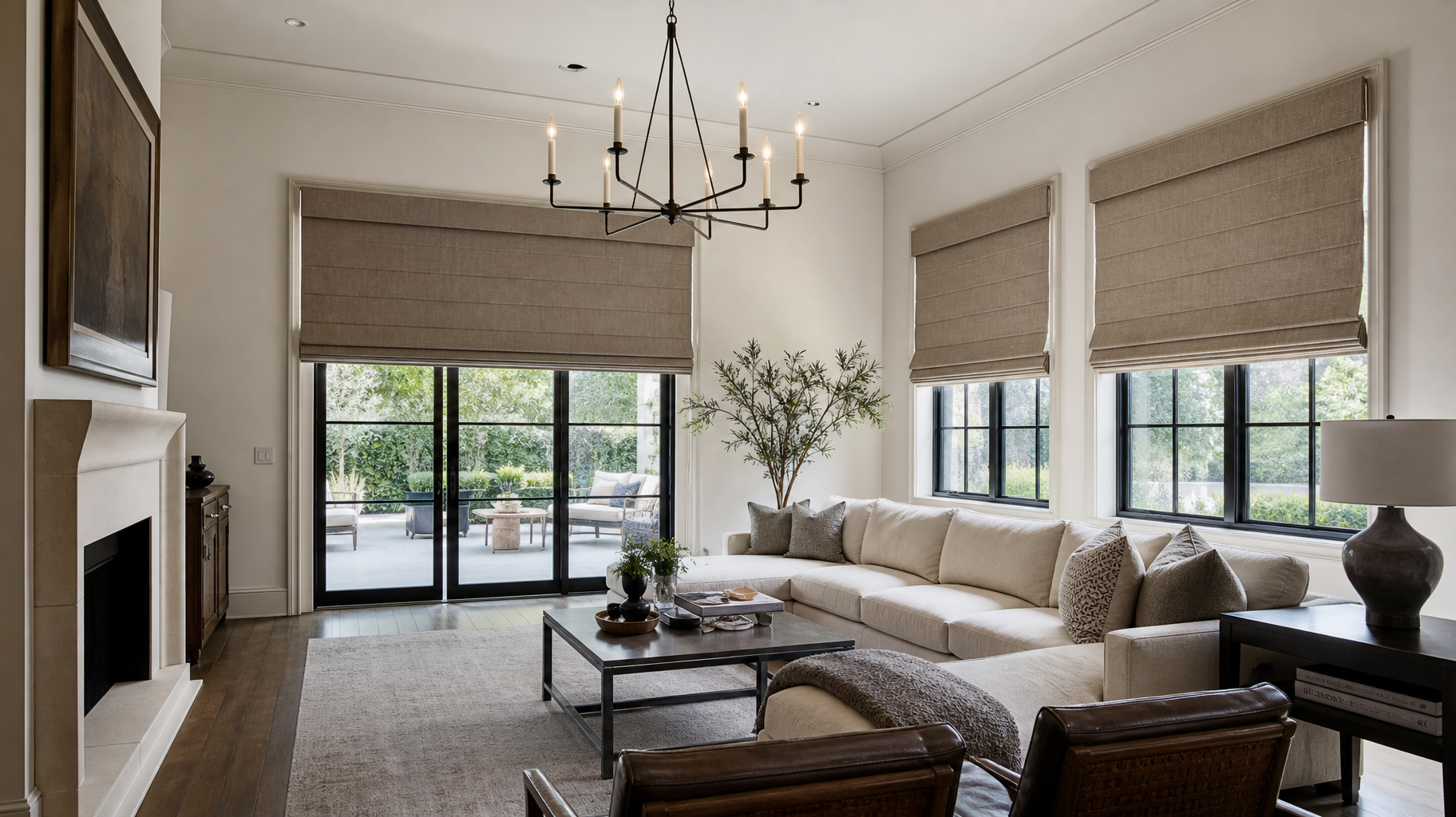 Elegant living room with beige sectional, chandelier, fireplace, and large windows with roman shades