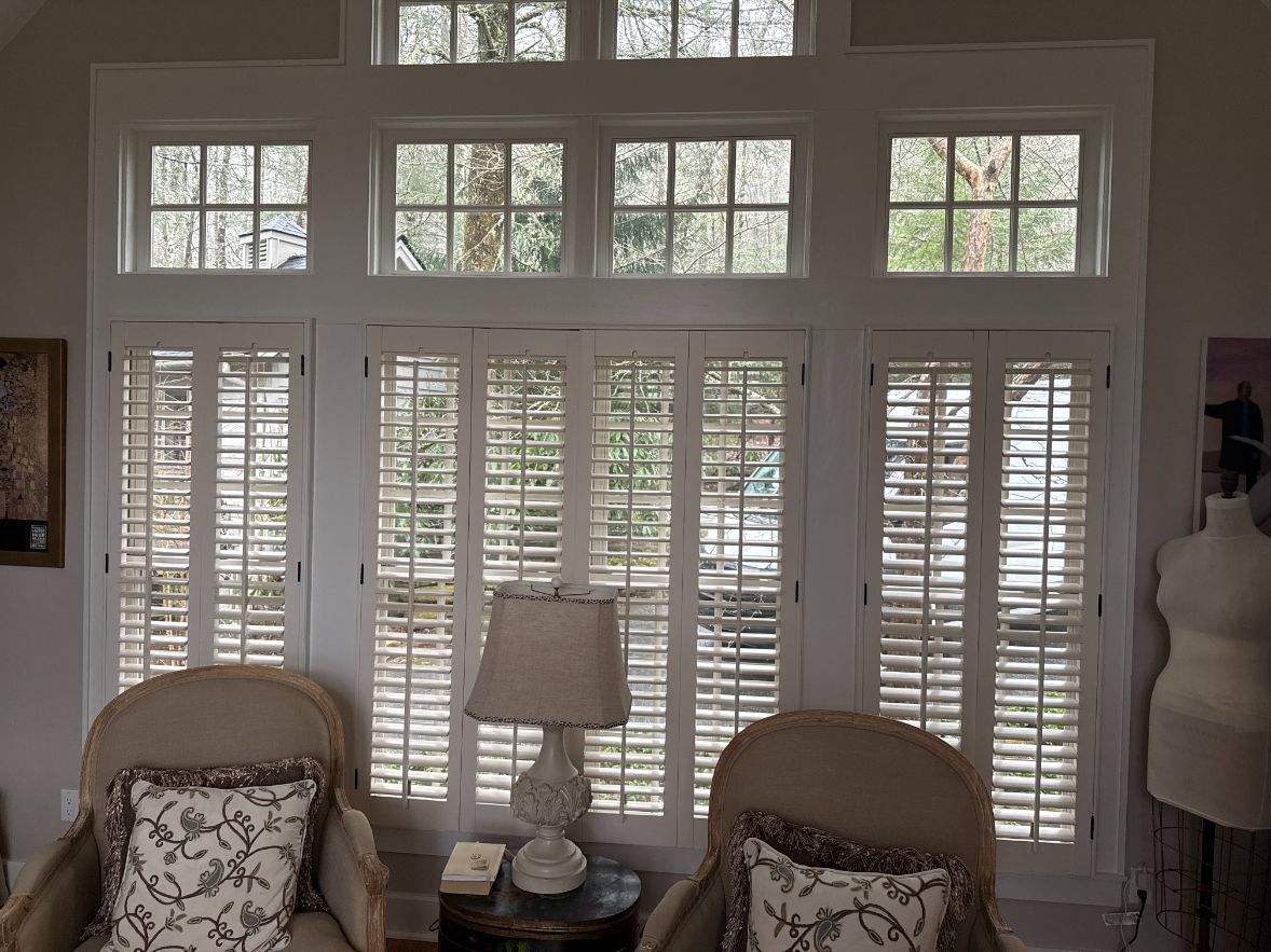 Living room with white shutters, two wicker chairs, and a lamp between them
