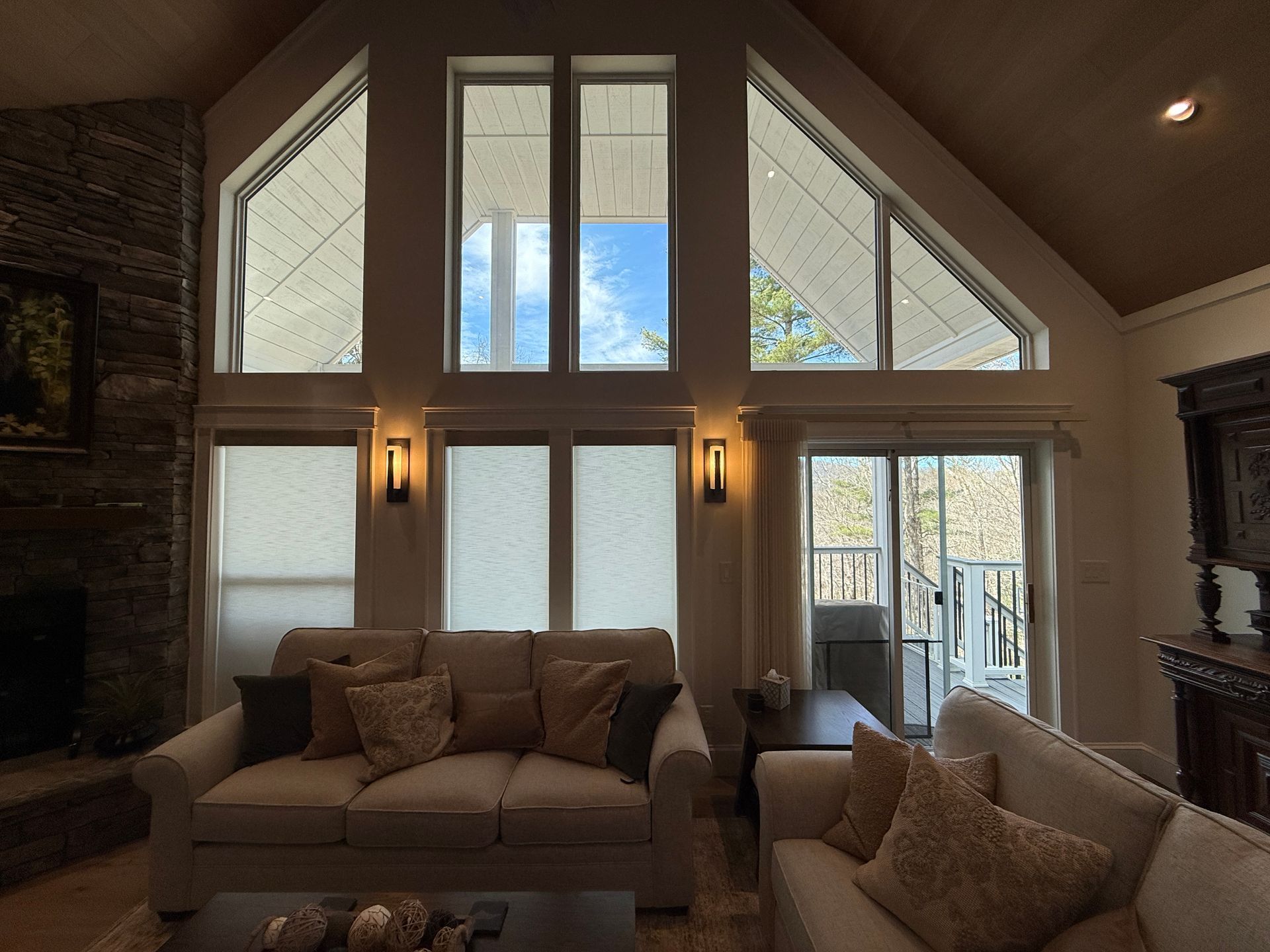 Living room with large windows, vaulted ceiling, and tan sofas in warm natural light
