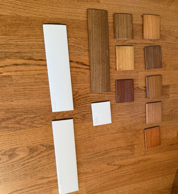 Wooden surface with laminated sample strips and small wood finish swatches arranged in a grid.
