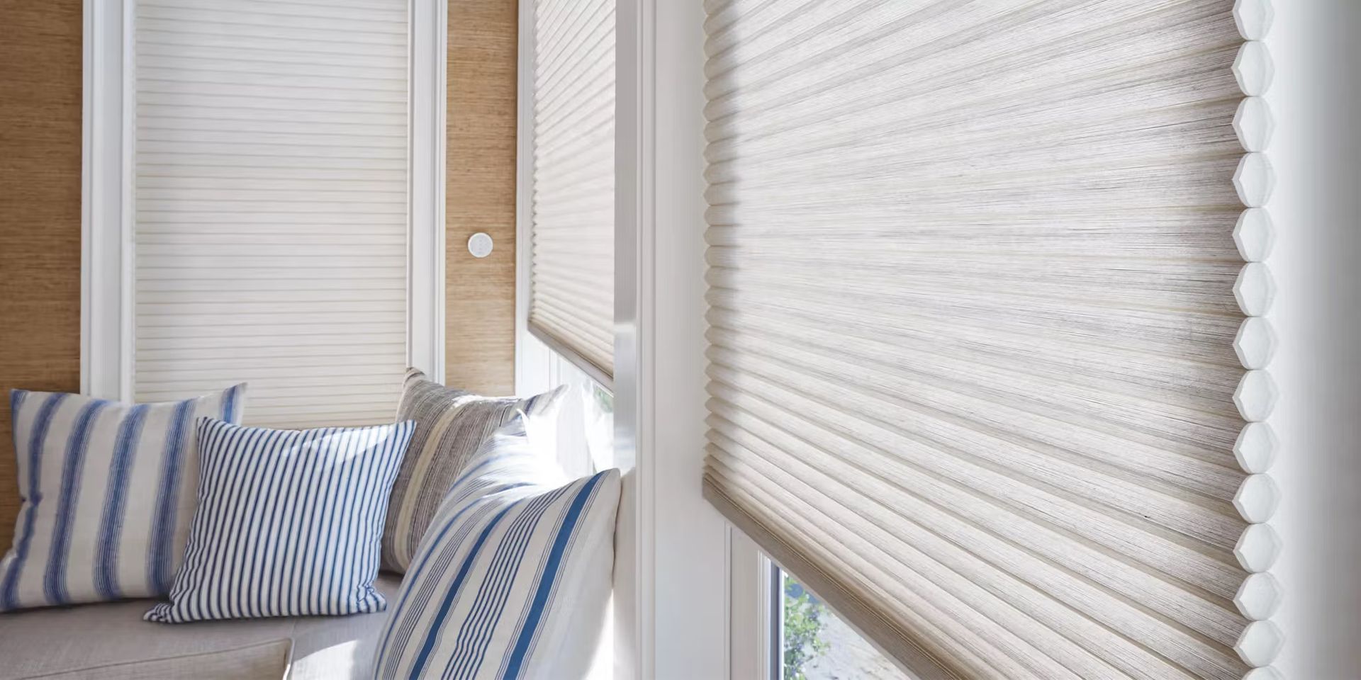 Cozy window nook with striped pillows and white pleated blinds in soft natural light