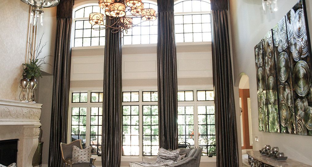 Elegant living room with tall windows, sheer curtains, chandelier, fireplace, and abstract wall art
