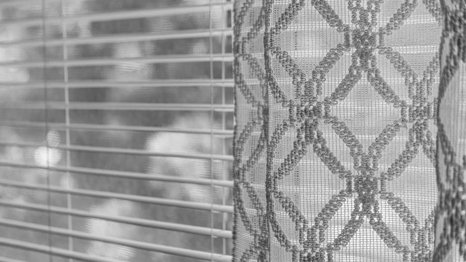 Closed blinds beside a lace curtain, with soft light filtering through the window.