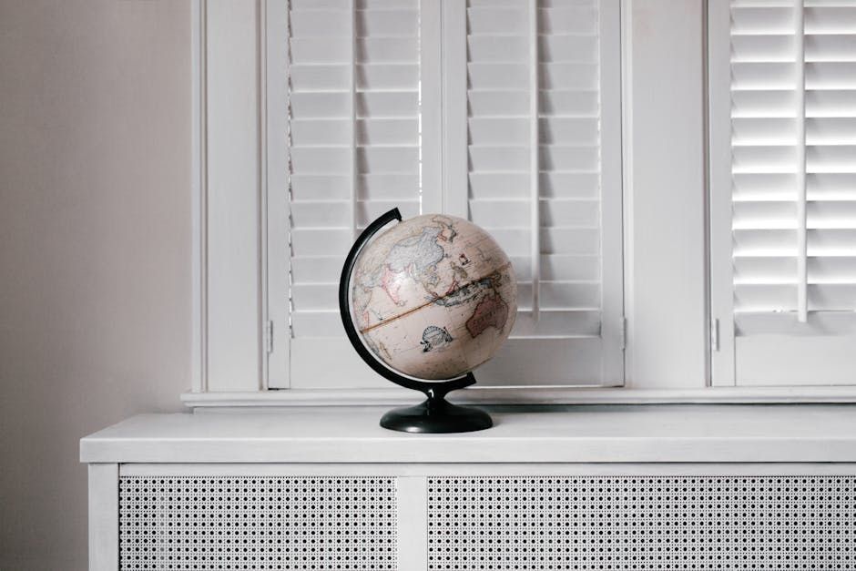 Small globe on a white cabinet in front of white window blinds