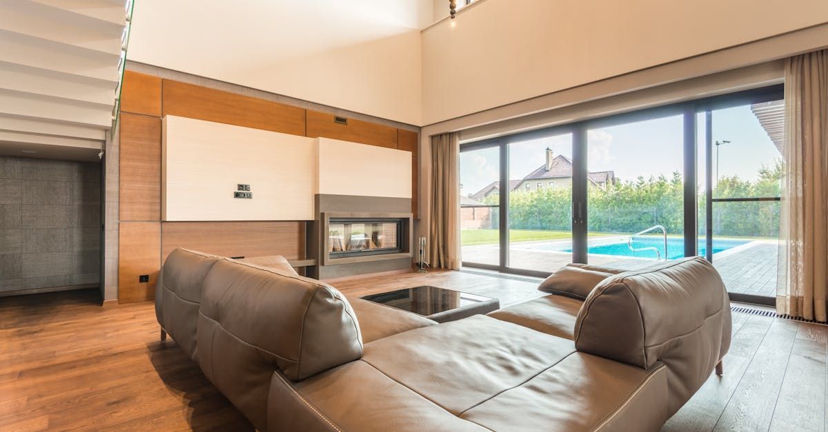 Spacious modern living room with leather sofa, fireplace, and sliding glass doors opening to a pool and yard