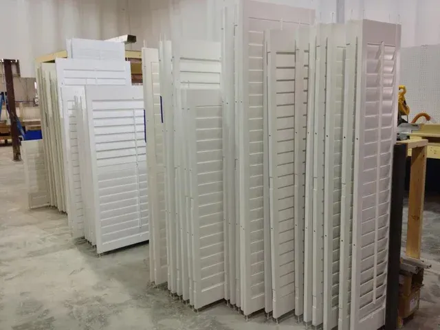 Stacks of white louvered shutters in a workshop or warehouse