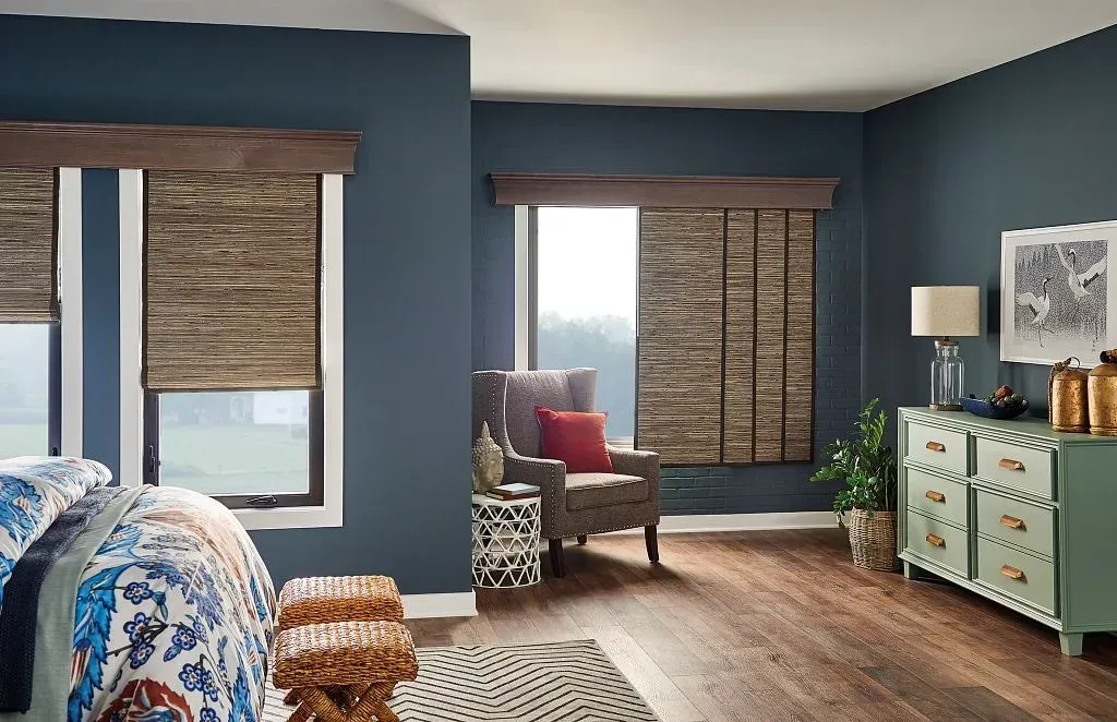 Blue living room with wooden blinds, patterned chairs, mint dresser, and potted plant near a bright window