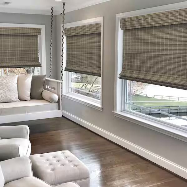 Bright living room with woven blinds on large windows, white built-in bench, and dark hardwood floors.
