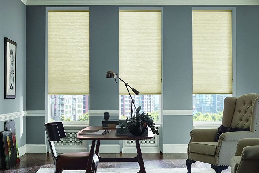 Bright living room with three windows, desk lamp, coffee table, and beige armchair by the window.