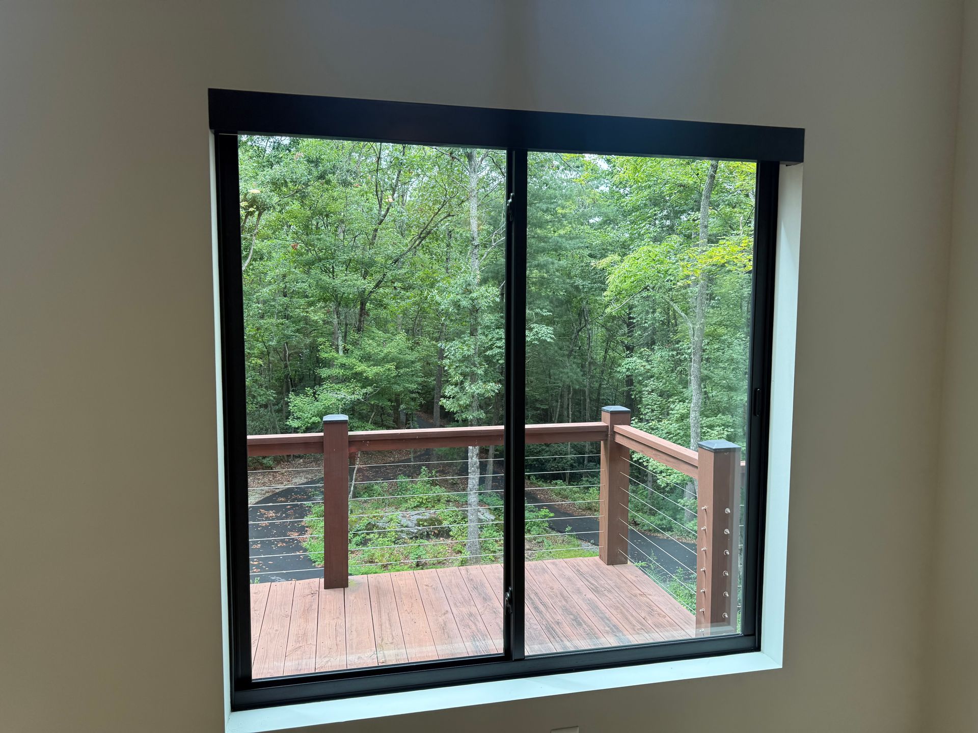 Sliding glass door overlooking a wooden deck and dense green trees