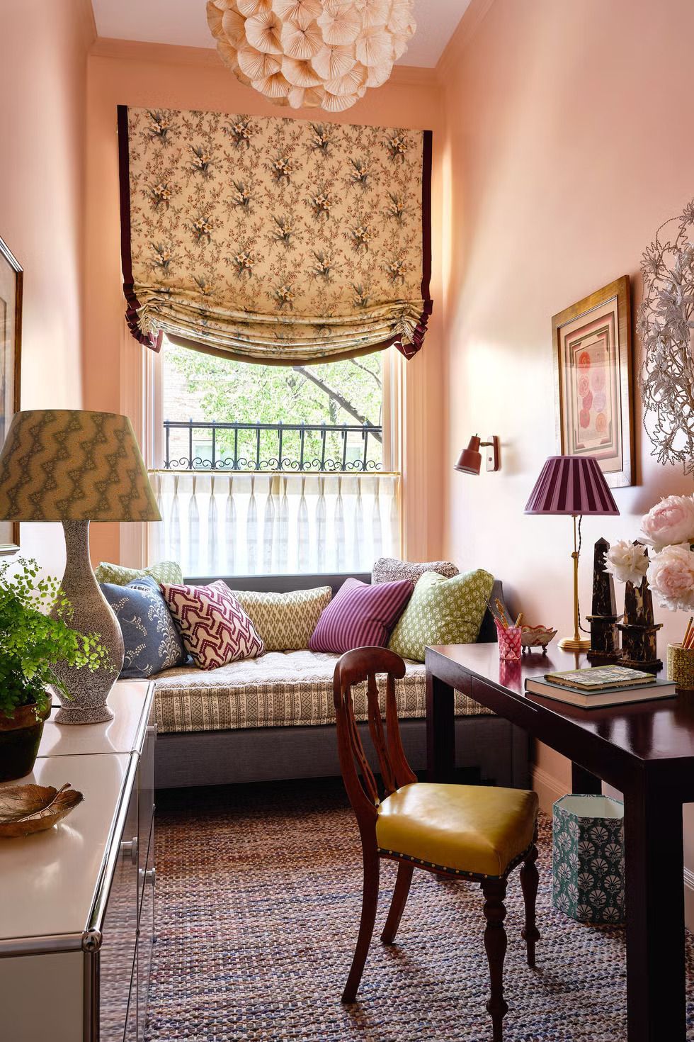 Cozy pink sitting room with a window seat, patterned curtains, dark desk, and yellow chair