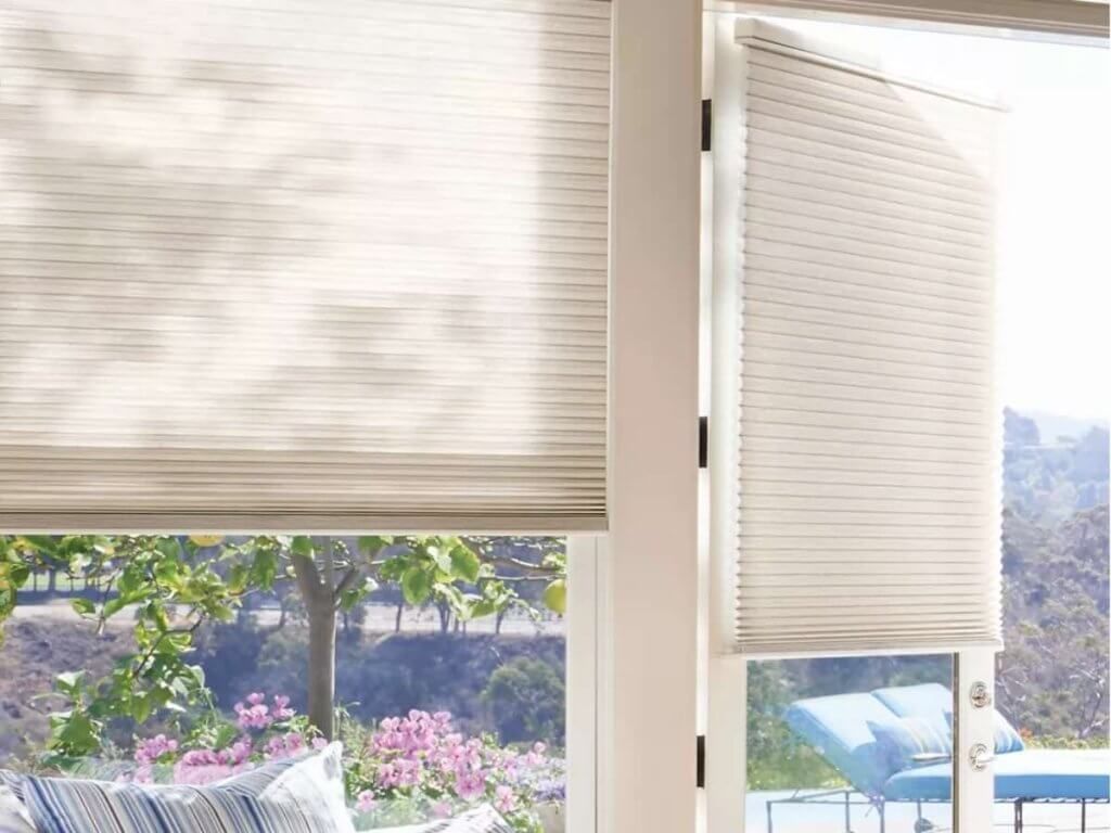 Partially raised window blinds with a garden and pool visible outside