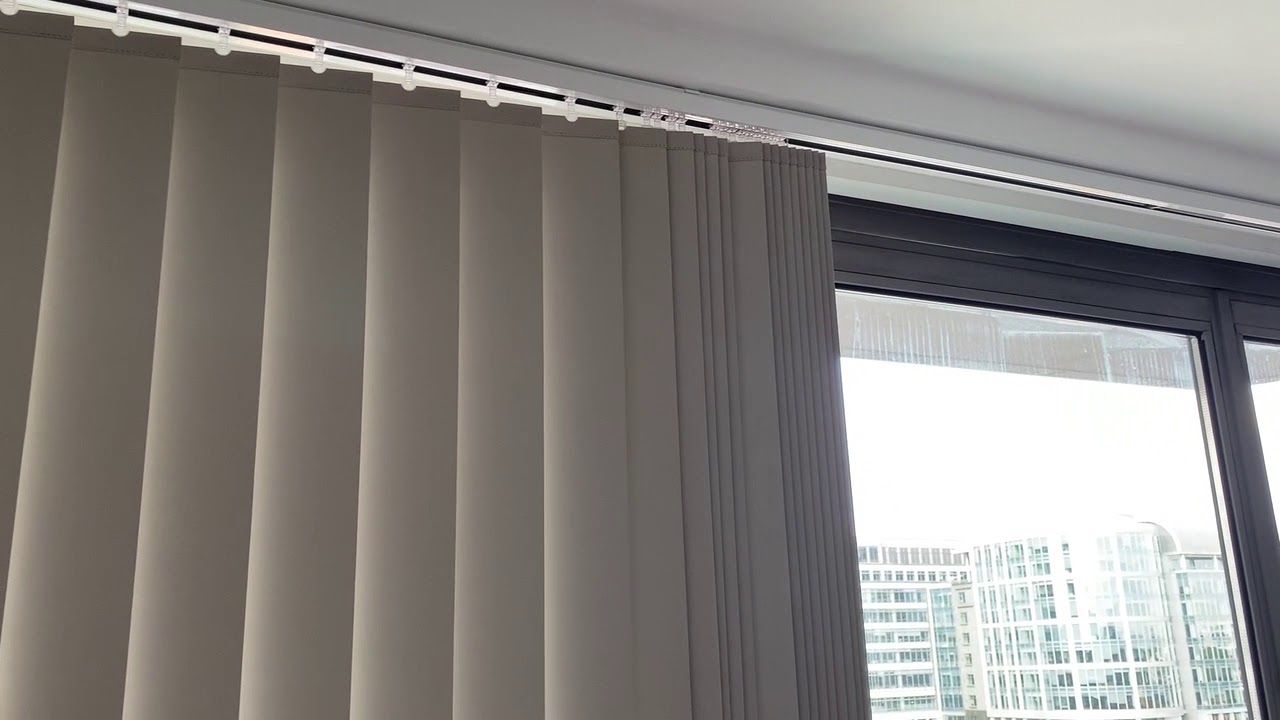 White curtains beside a large window overlooking city buildings