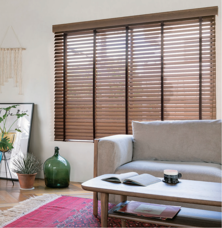 Cozy living room with a sofa, wooden coffee table, potted plants, and brown window blinds