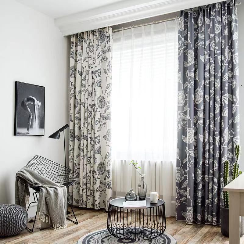 Bright living room with patterned curtains, a chair, round coffee table, and framed wall art