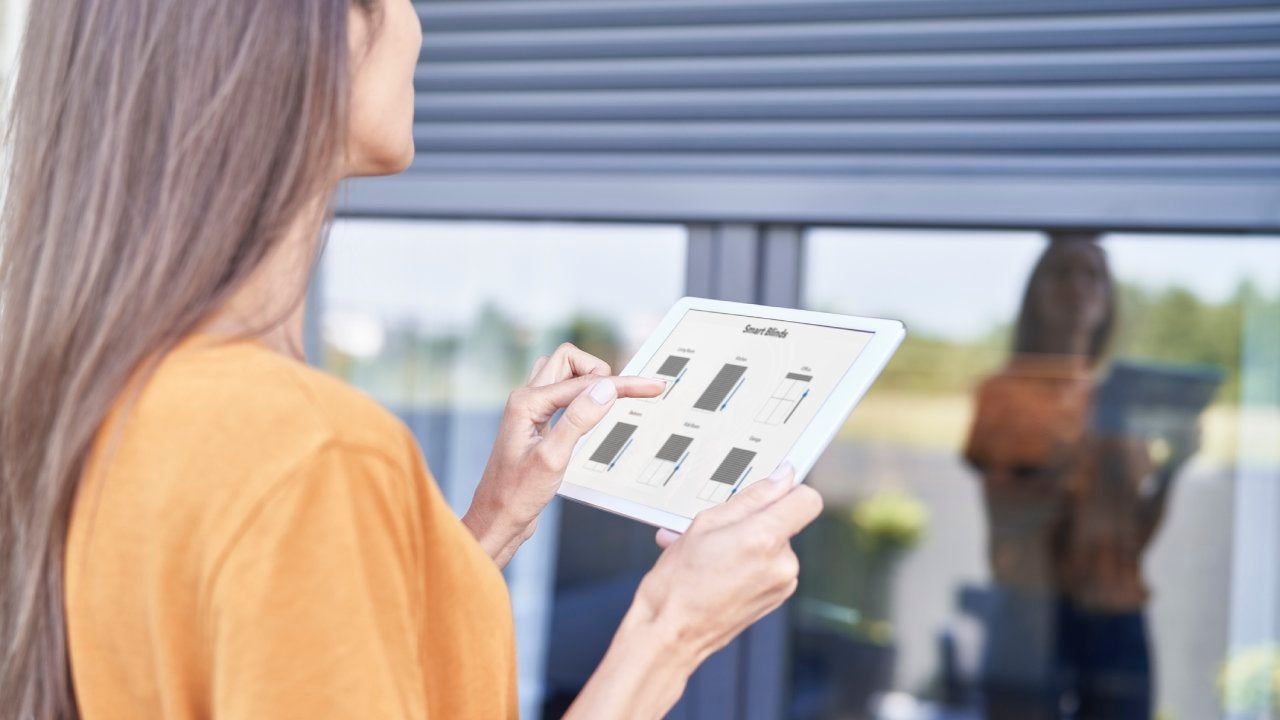 Person in orange top reviewing a tablet with fabric samples beside a window