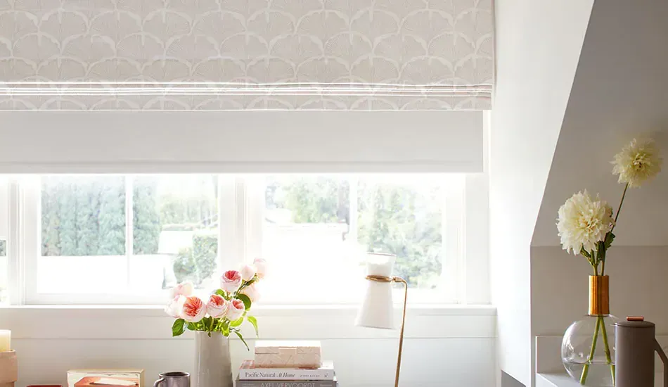 Bright sunlit room with large window, white desk, flowers, lamp, and patterned wall trim