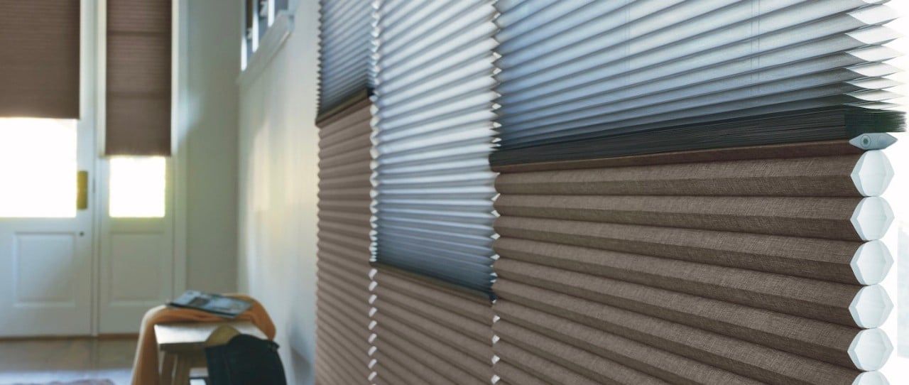 Blinds on windows in a bright room, with a door and chair in the background