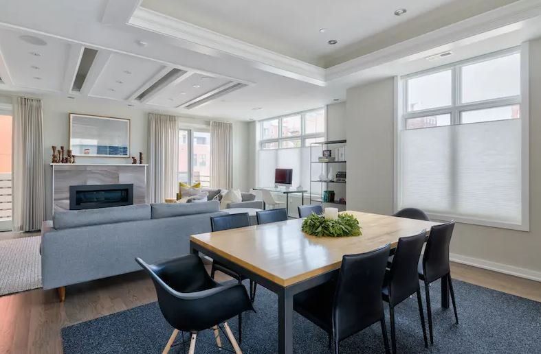 Modern open-plan living and dining room with gray sofas, round table, and large windows