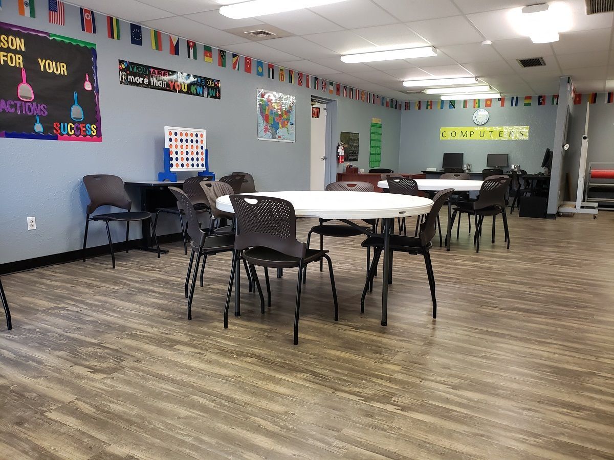 A large room at Unified Residential Homes with tables and chairs in it.