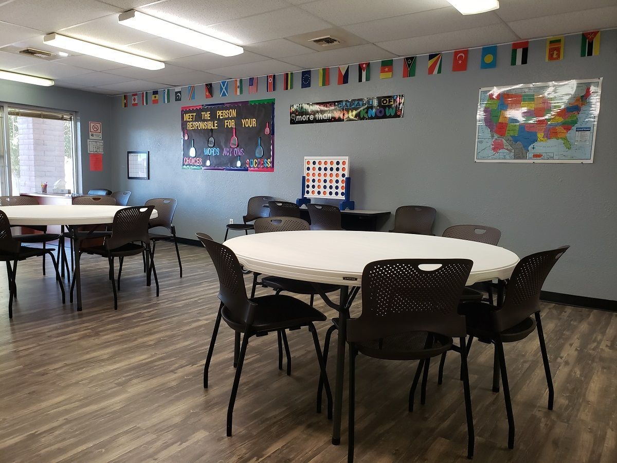A room at Unified Residential Homes with tables and chairs and flags on the wall.