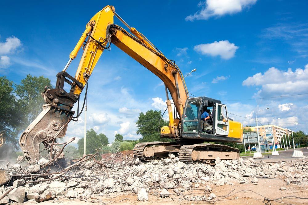 A Yellow Excavator Is Demolishing A Building On A Construction Site — Ian Brown Sand Supplies and Tipper Hire In Port Macquarie, NSW