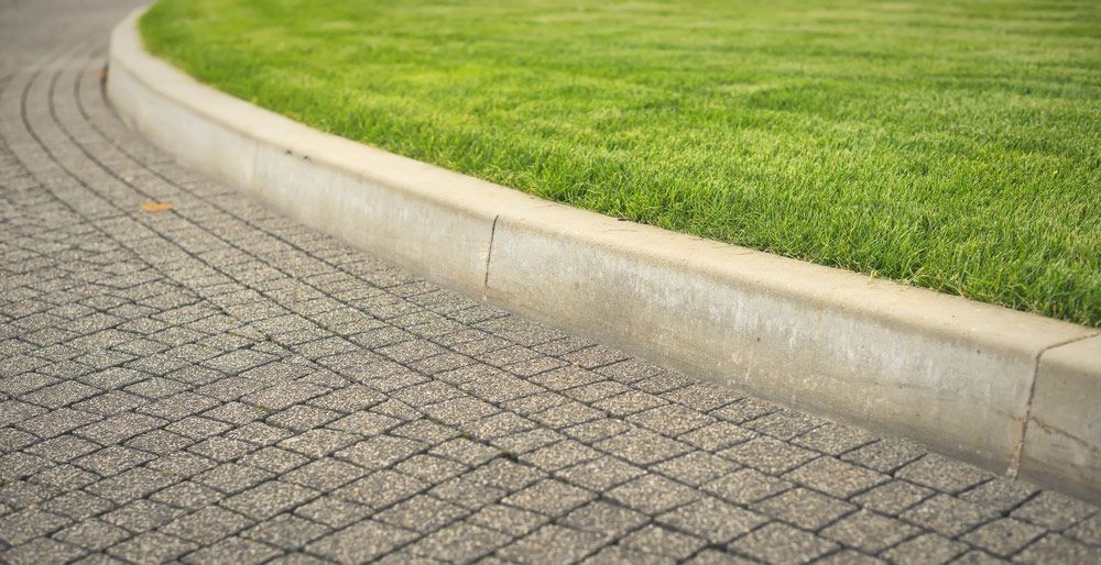 A Brick Curb Next To A Lush Green Lawn — Ian Brown Sand Supplies and Tipper Hire In Port Macquarie, NSW