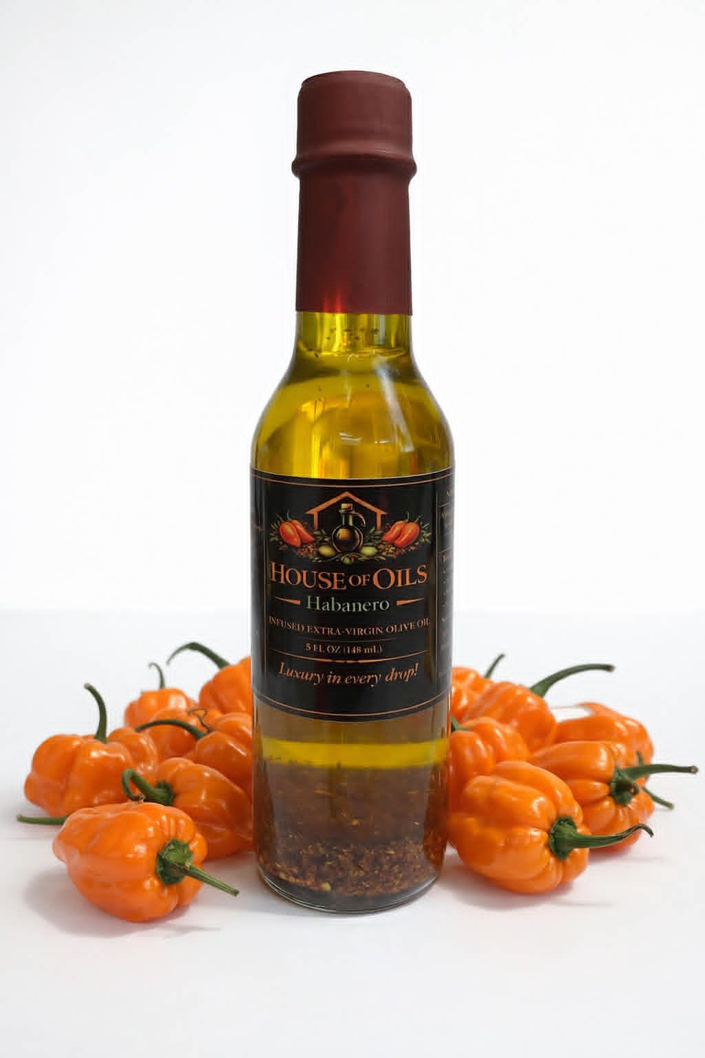 Bottle of habanero sauce or oil surrounded by orange mini pumpkins on a white background