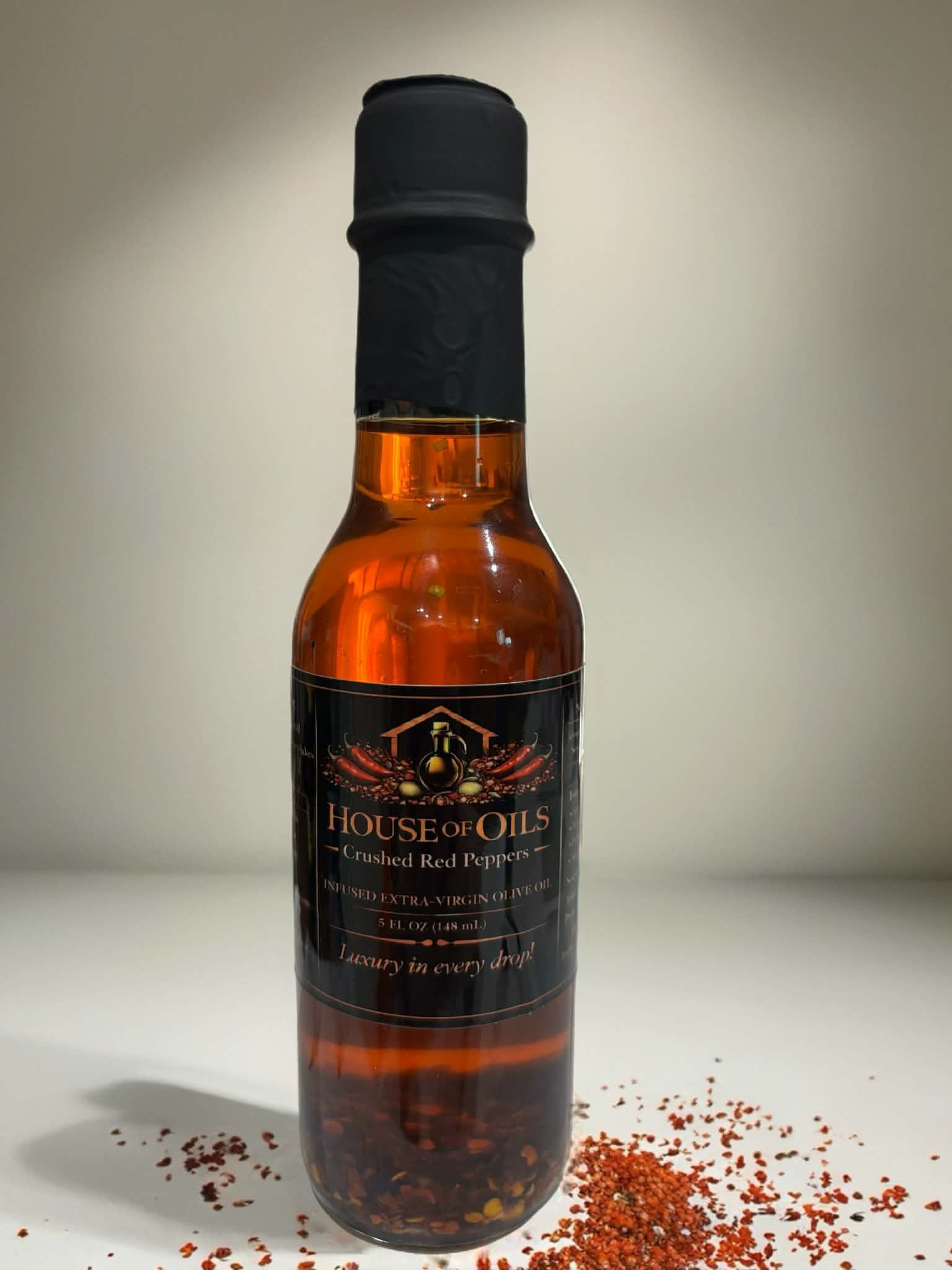 Amber bottle with black label and cap, surrounded by scattered red spices on a white surface.