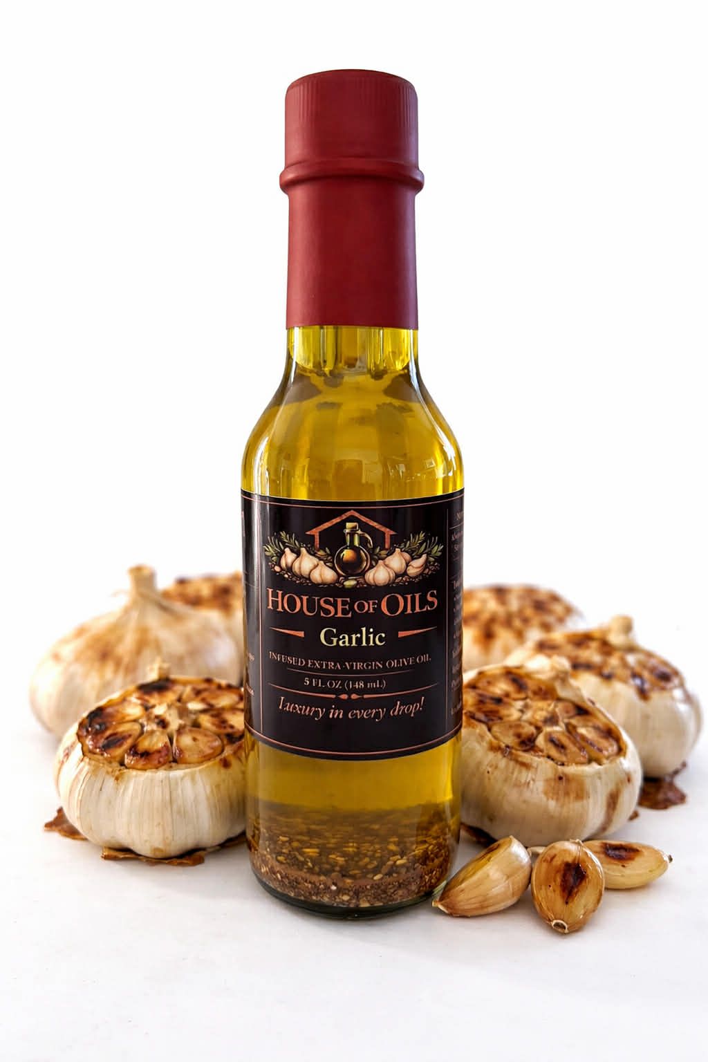 Bottle of garlic-infused oil with garlic bulbs and cloves on a white background