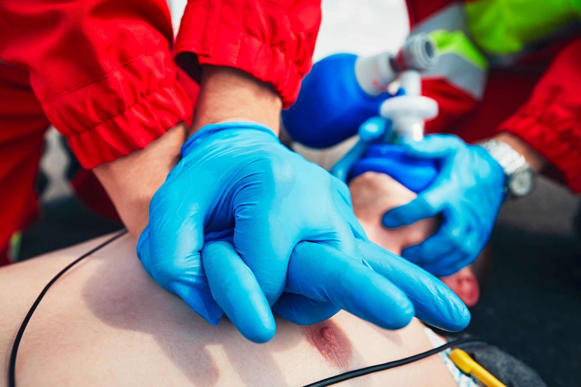 Blue-gloved hands using a syringe on a patient during a medical procedure