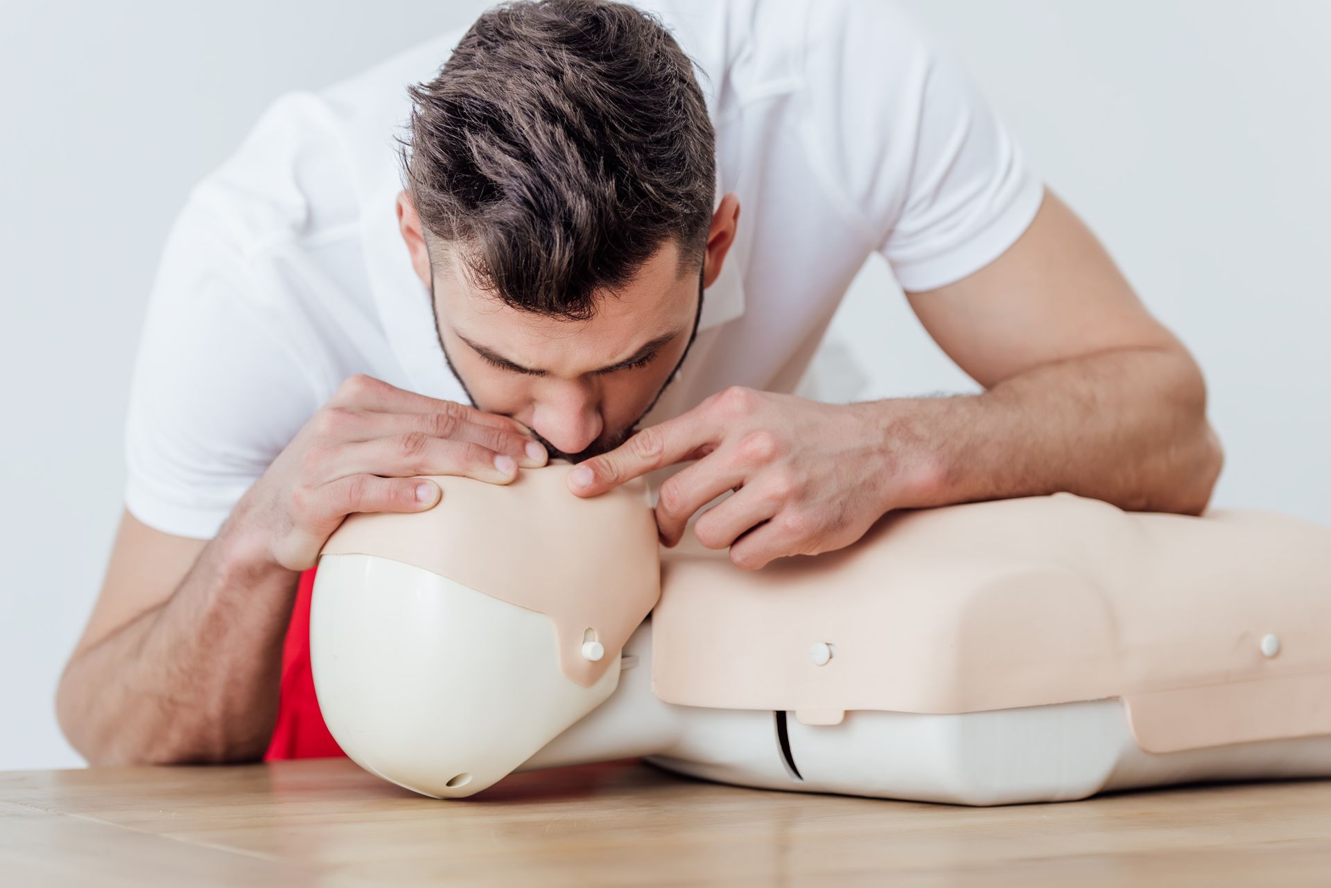 Man performing CPR chest compressions on a CPR training mannequin