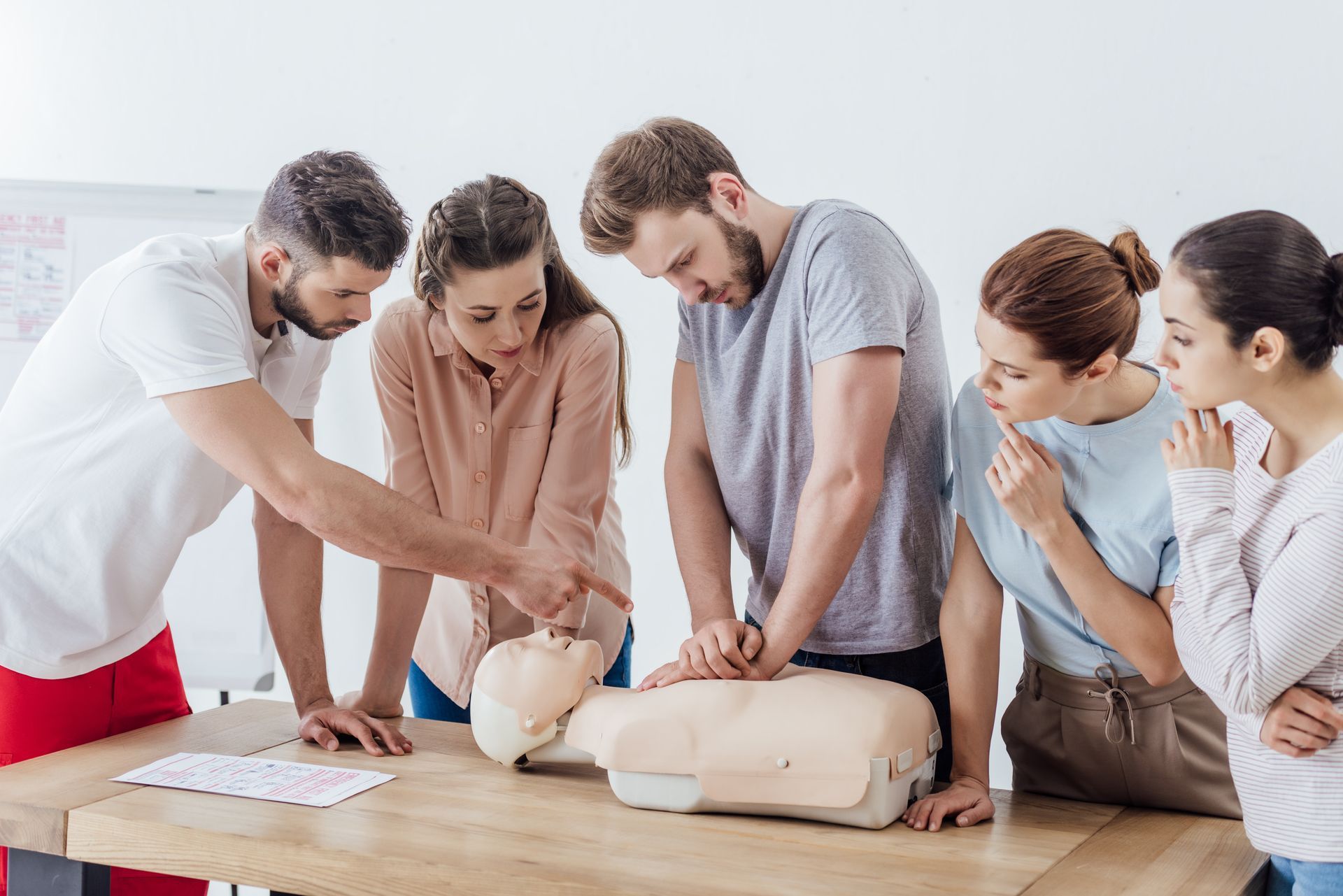 Group practicing CPR on mannequins in a classroom setting