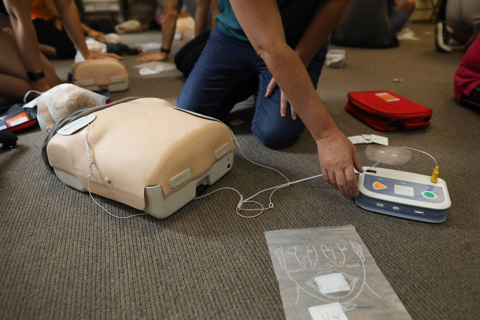 Training schedule materials next to an AED trainer unit, representing the AED certification timeline.