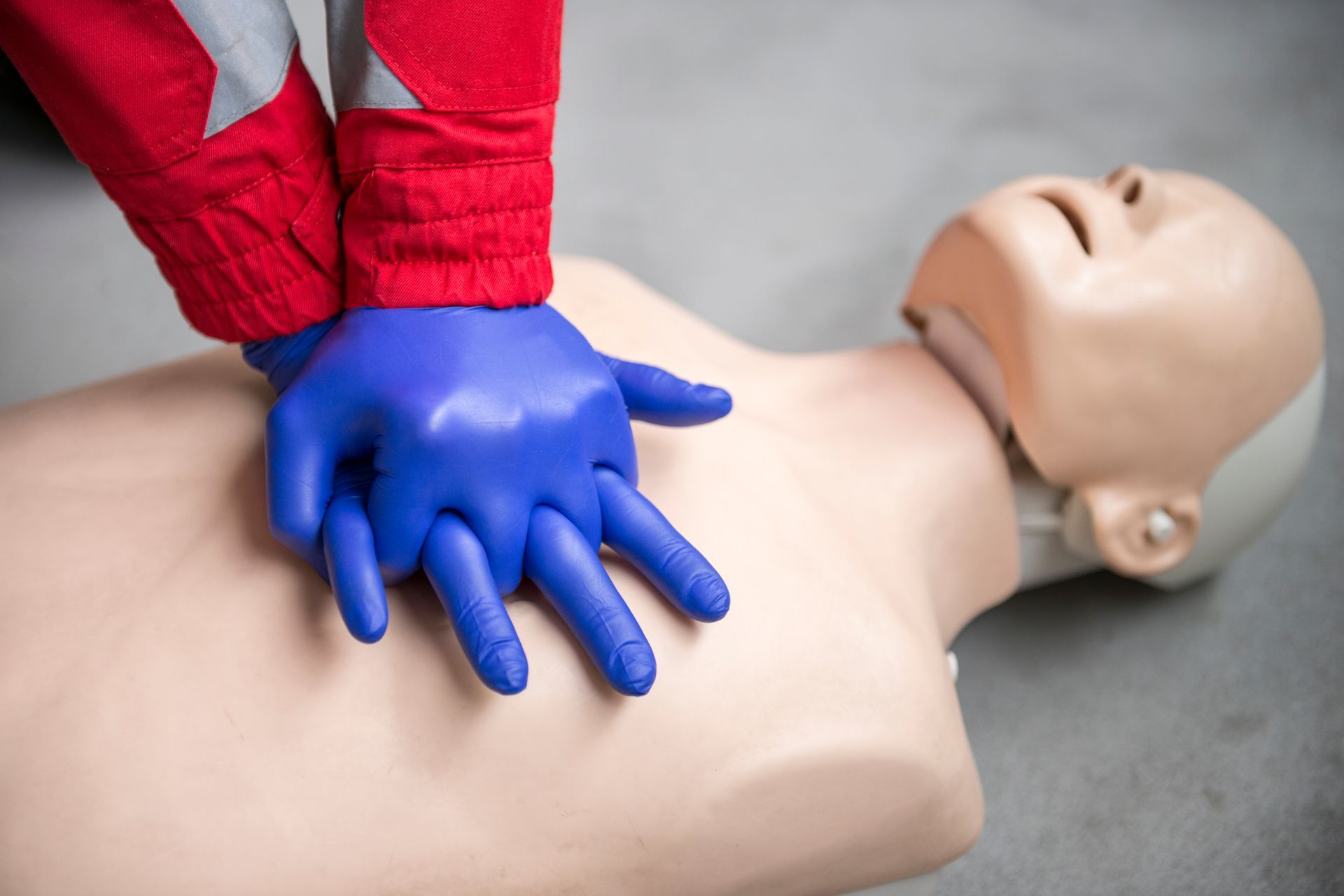 CPR training mannequin with gloved hands performing chest compressions