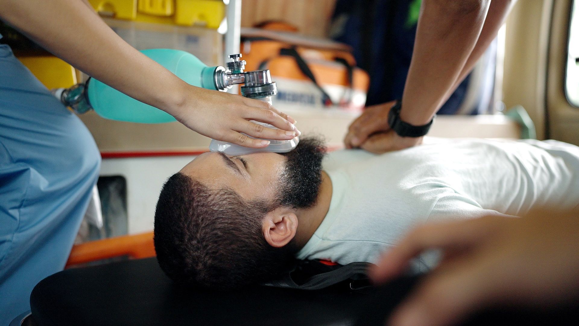 Paramedic using an oxygen mask on an injured person lying on a stretcher