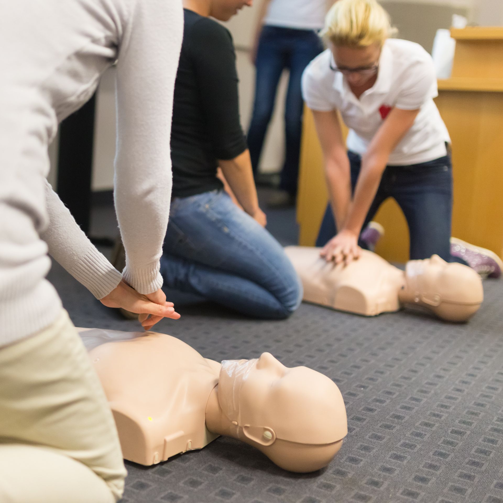 People practicing CPR on mannequins during first aid training