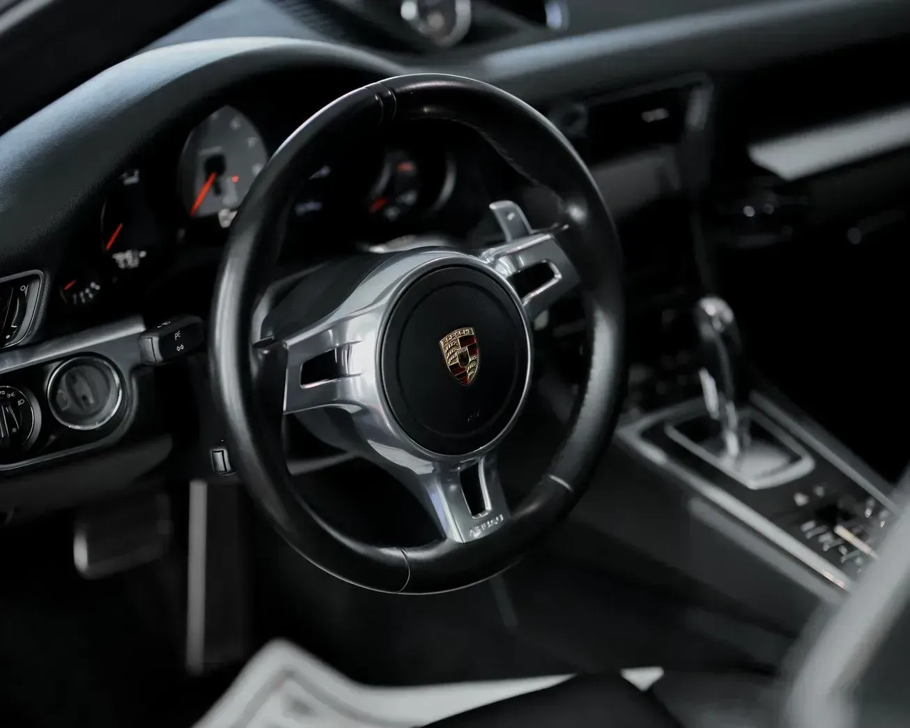 Interior of a Porsche sports car showing the steering wheel, dashboard, and gear shift.