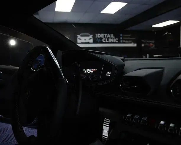 Interior view of a black Lamborghini. Dashboard and steering wheel are visible, with the