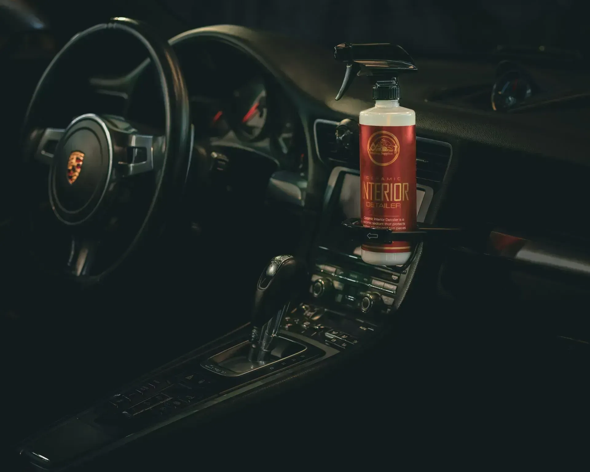 Interior of a Porsche sports car with car cleaning product bottle on the console.