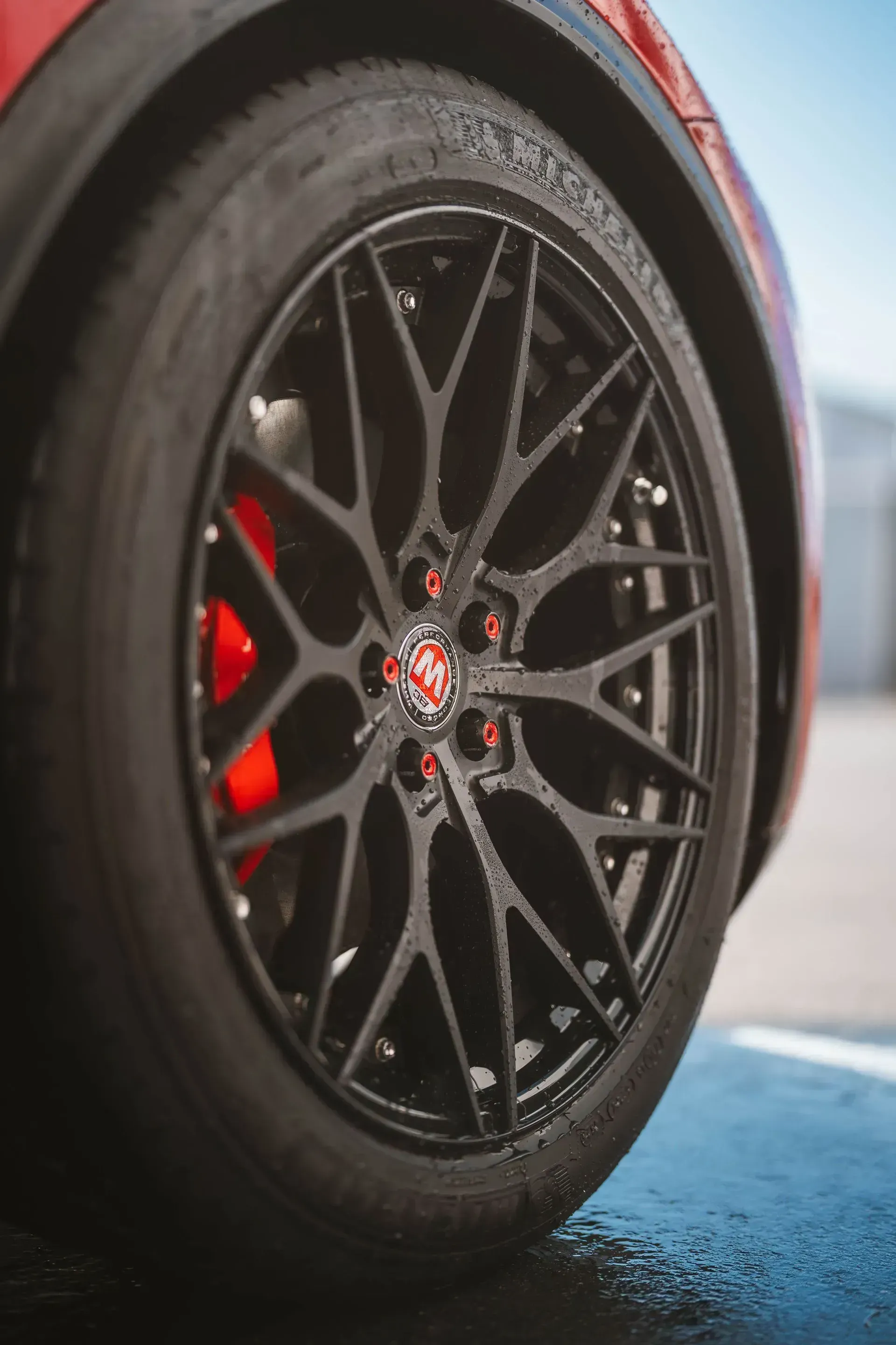 Black car wheel with red brake calipers and black spokes, close-up.