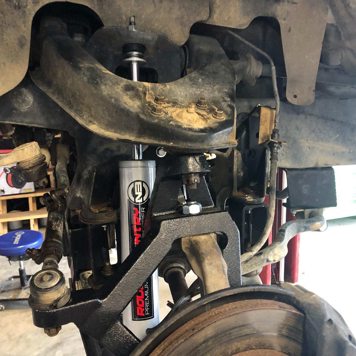 A truck's suspension system being worked on, showing shock absorbers and control arms.